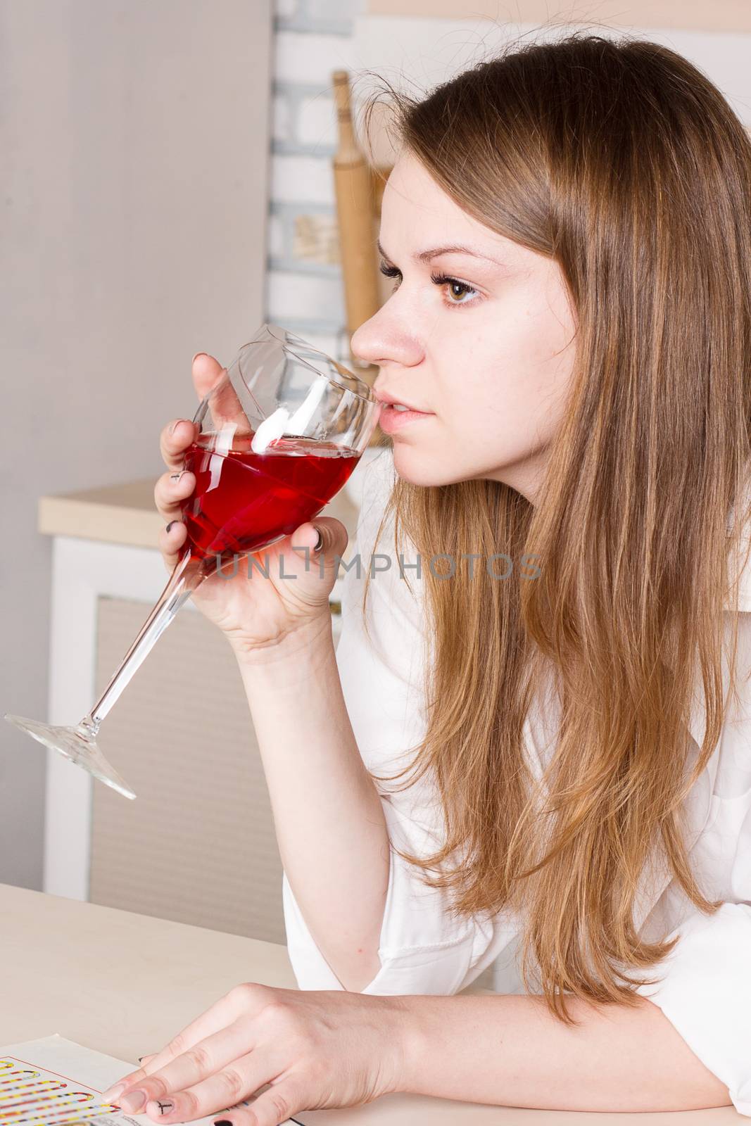 Woman drinking red wine in the kitchen