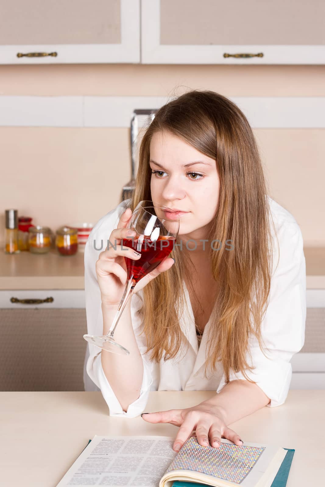 Girl with long flowing hair in  shirt in the kitchen with a glass of red wine