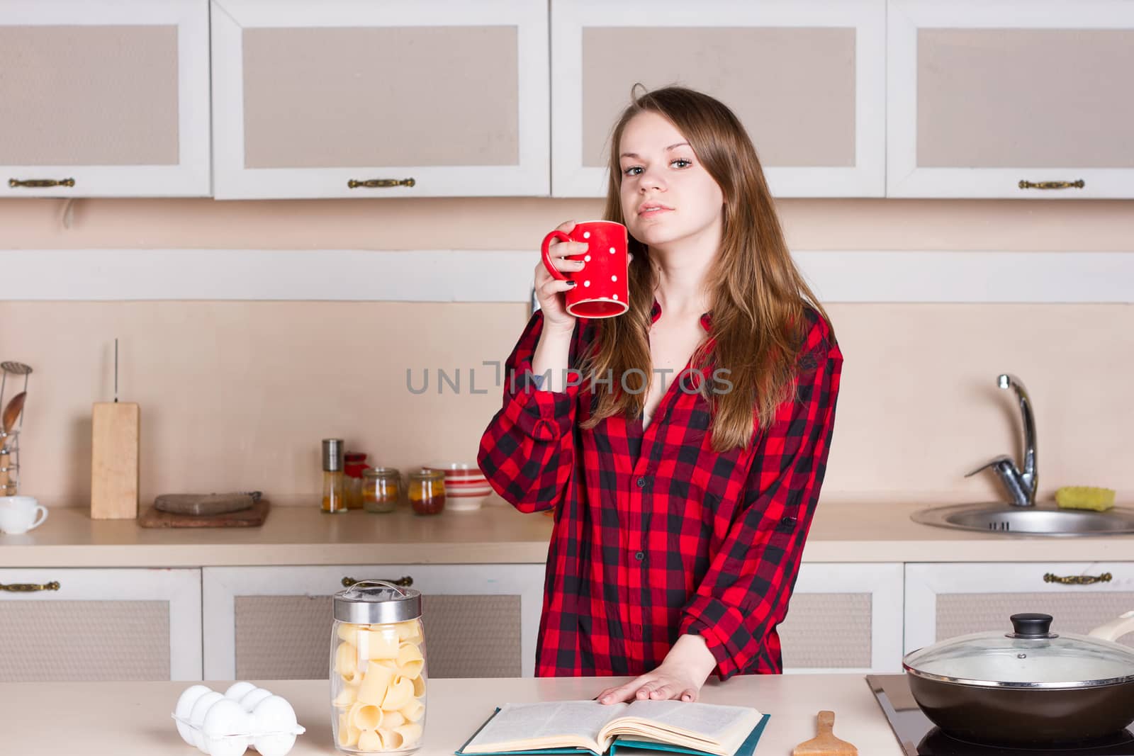 Girl with long flowing hair in a red men's shirt. kitchen cup his hands by victosha