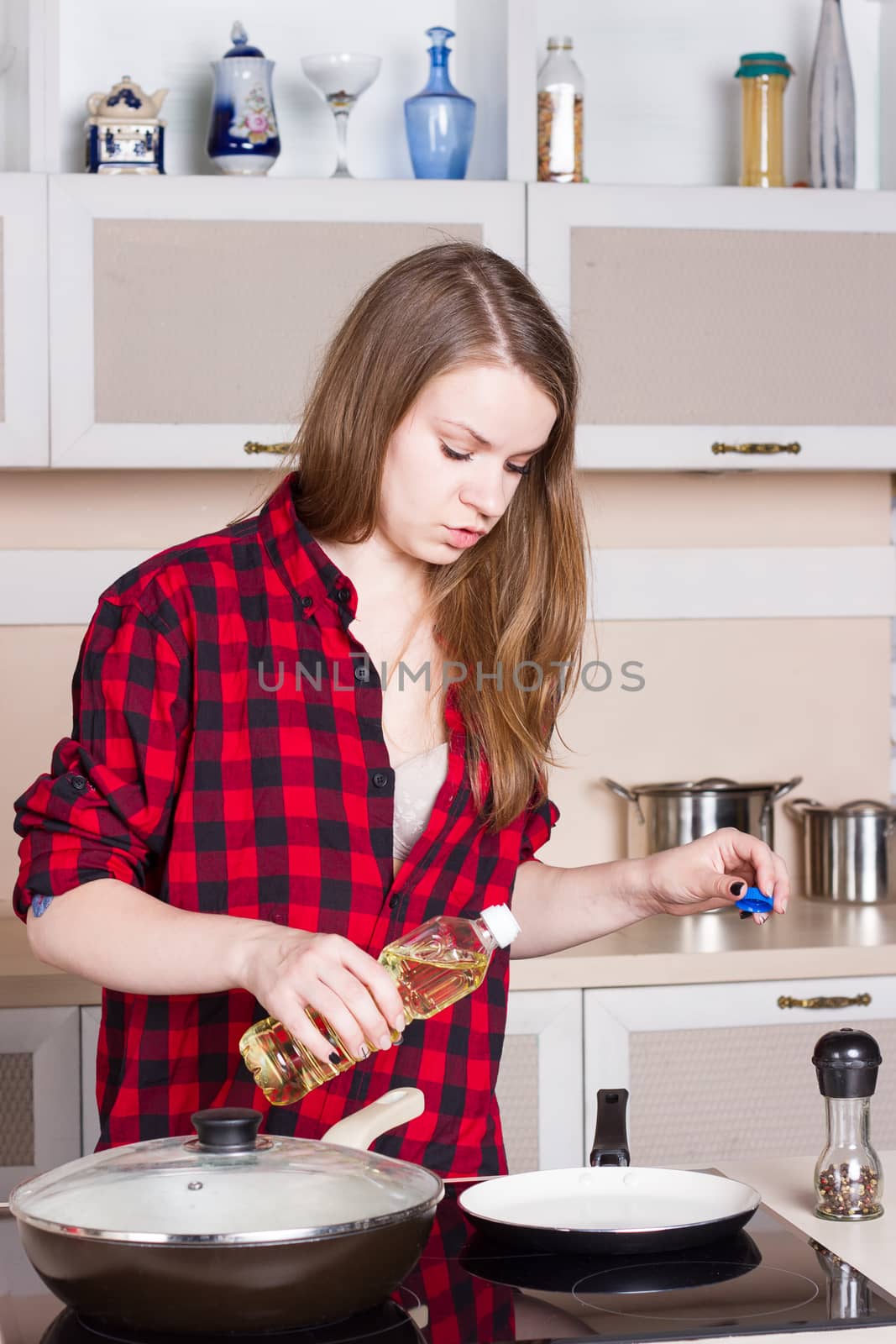 Girl with long flowing hair in a red shirt male prepares in the kitchen. Vertical framing