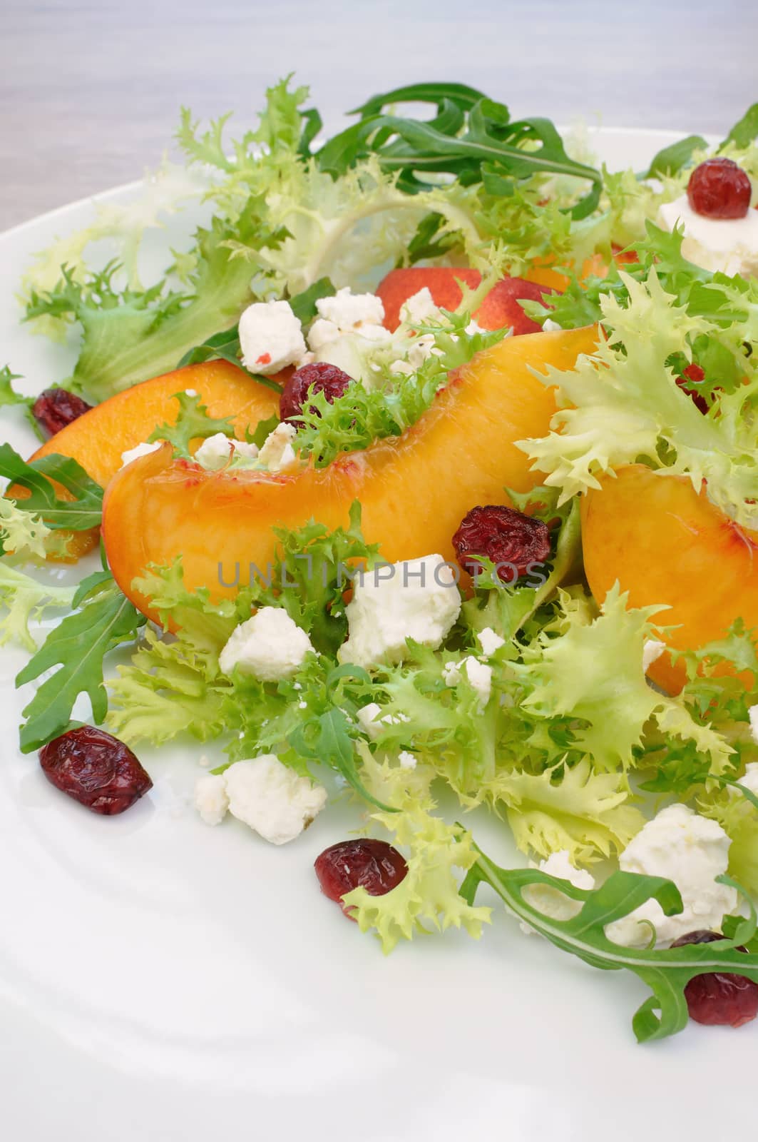 Salad of lettuce and arugula with peaches, feta cheese, cranberries