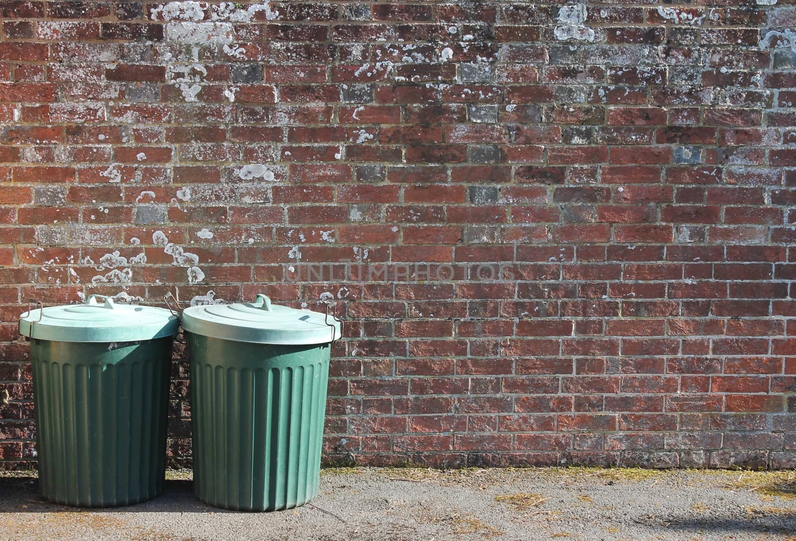 trash can dustbins outside against brick wall