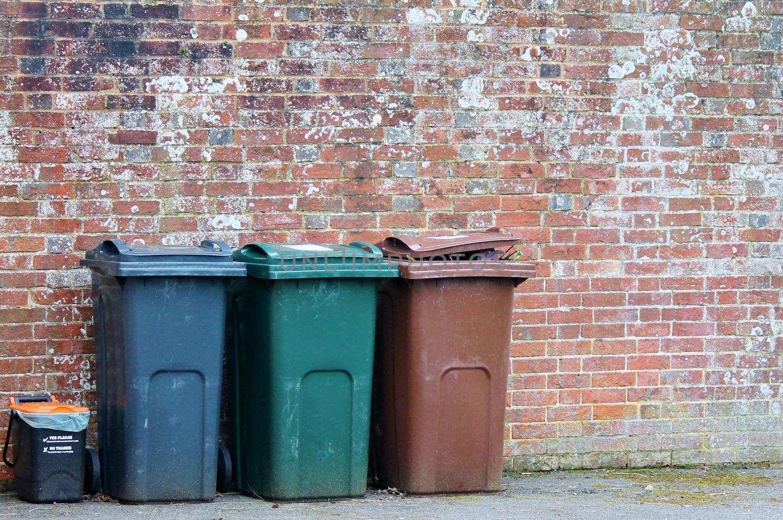 Trash can dustbins outside against brick wall 