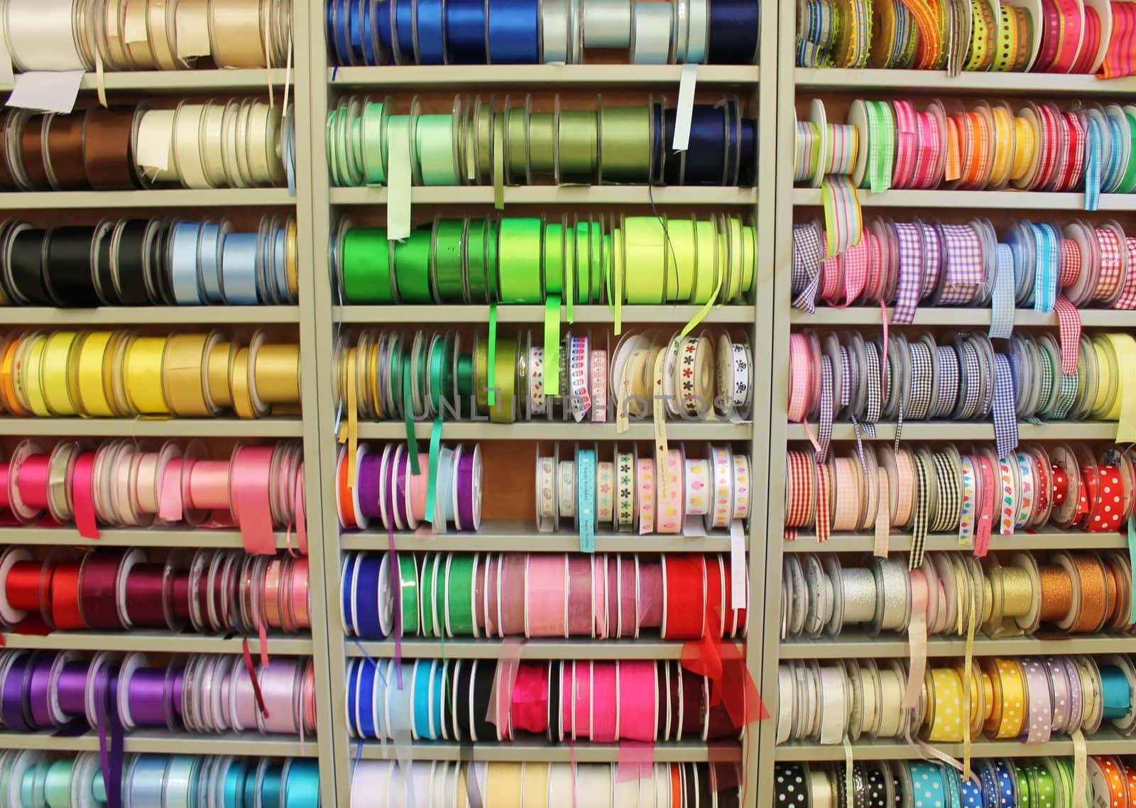 haberdashery shelves of colourful ribbon reels rows and trims in fabric shop by cheekylorns