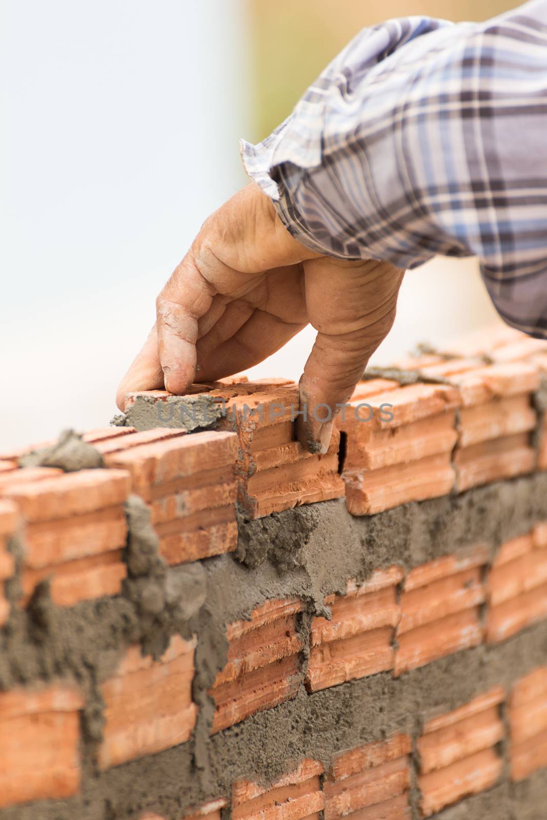 Bricklayer working in construction site of a brick wall by stoonn