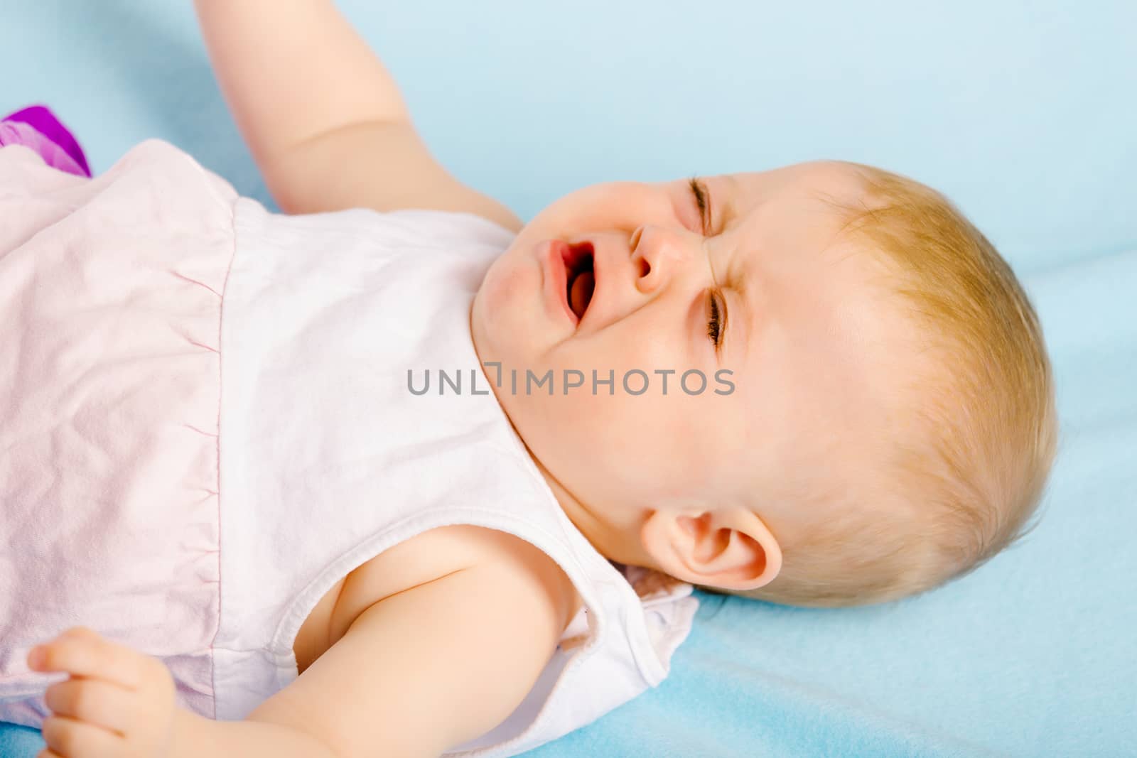 Crying baby lying on a blue plaid
