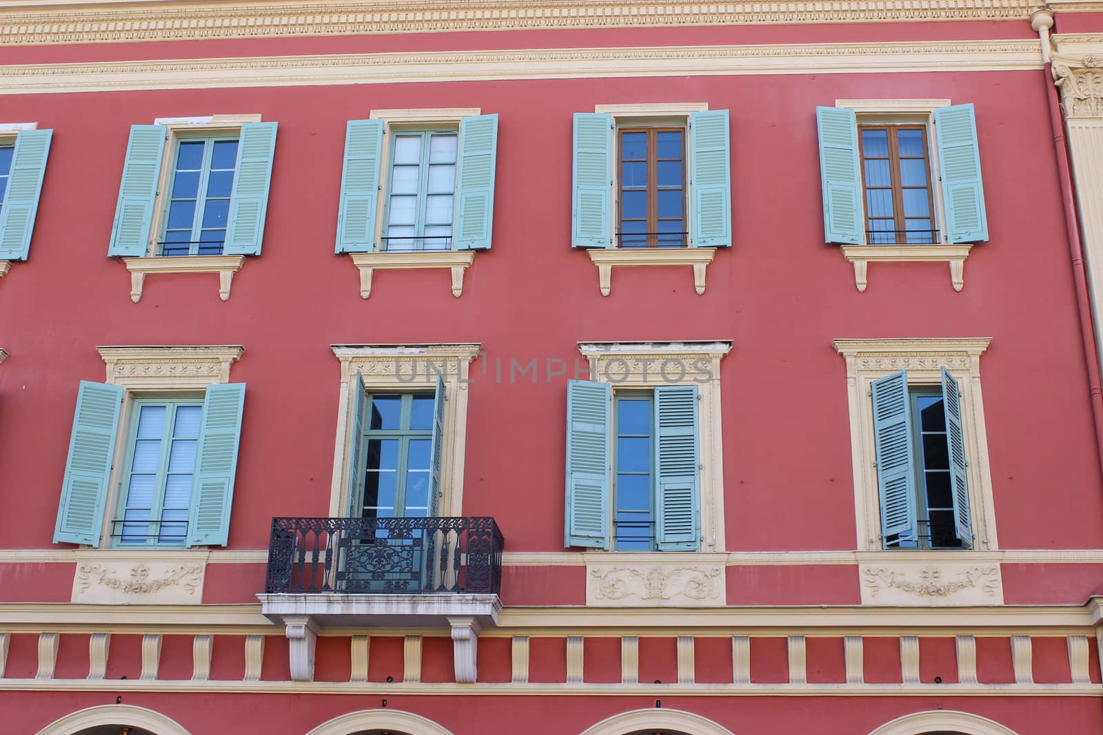 Beautiful pink facade of a building. Blue Shutters. Place Massena in Nice, France
