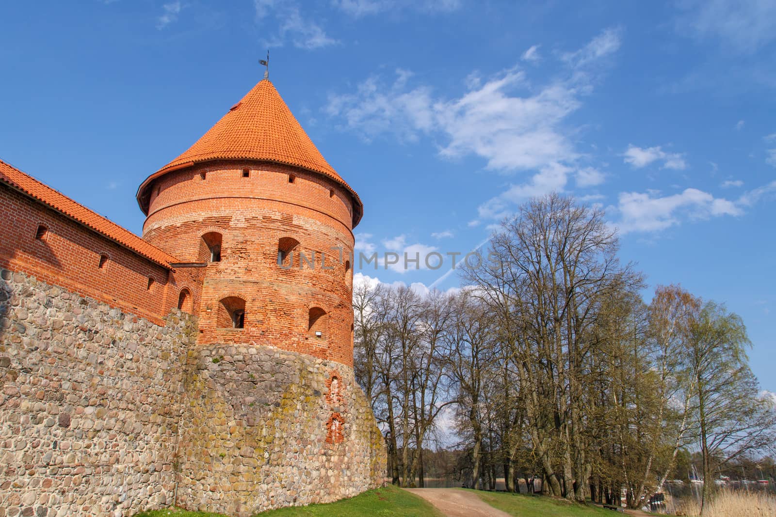 View of Trakai Castle with brown bricks and stonewalls, on cloudy sky background.