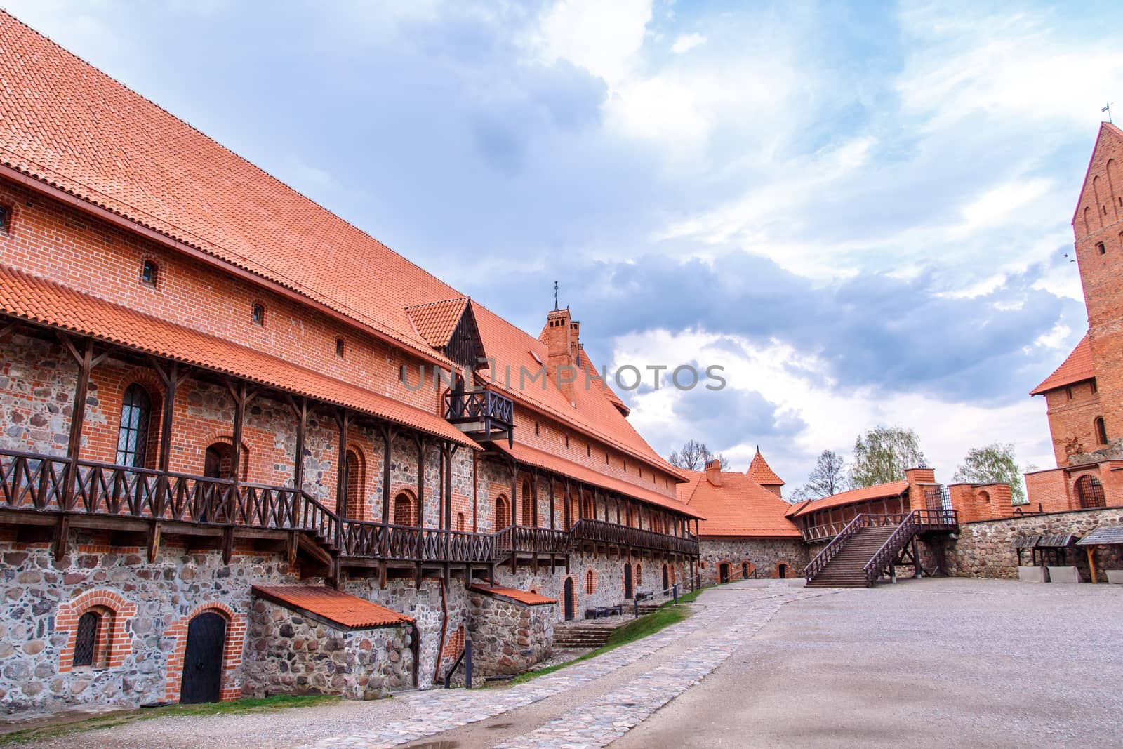 View of Trakai Castle and buildings of it in Lithuania with high brown brickwalls, on cloudy sky background.