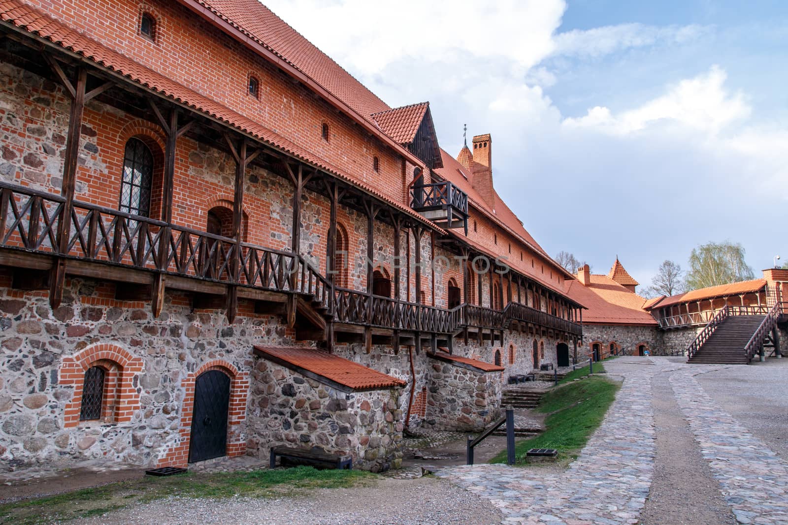 View of Trakai Castle and buildings of it in Lithuania with high brown brickwalls, on cloudy sky background.