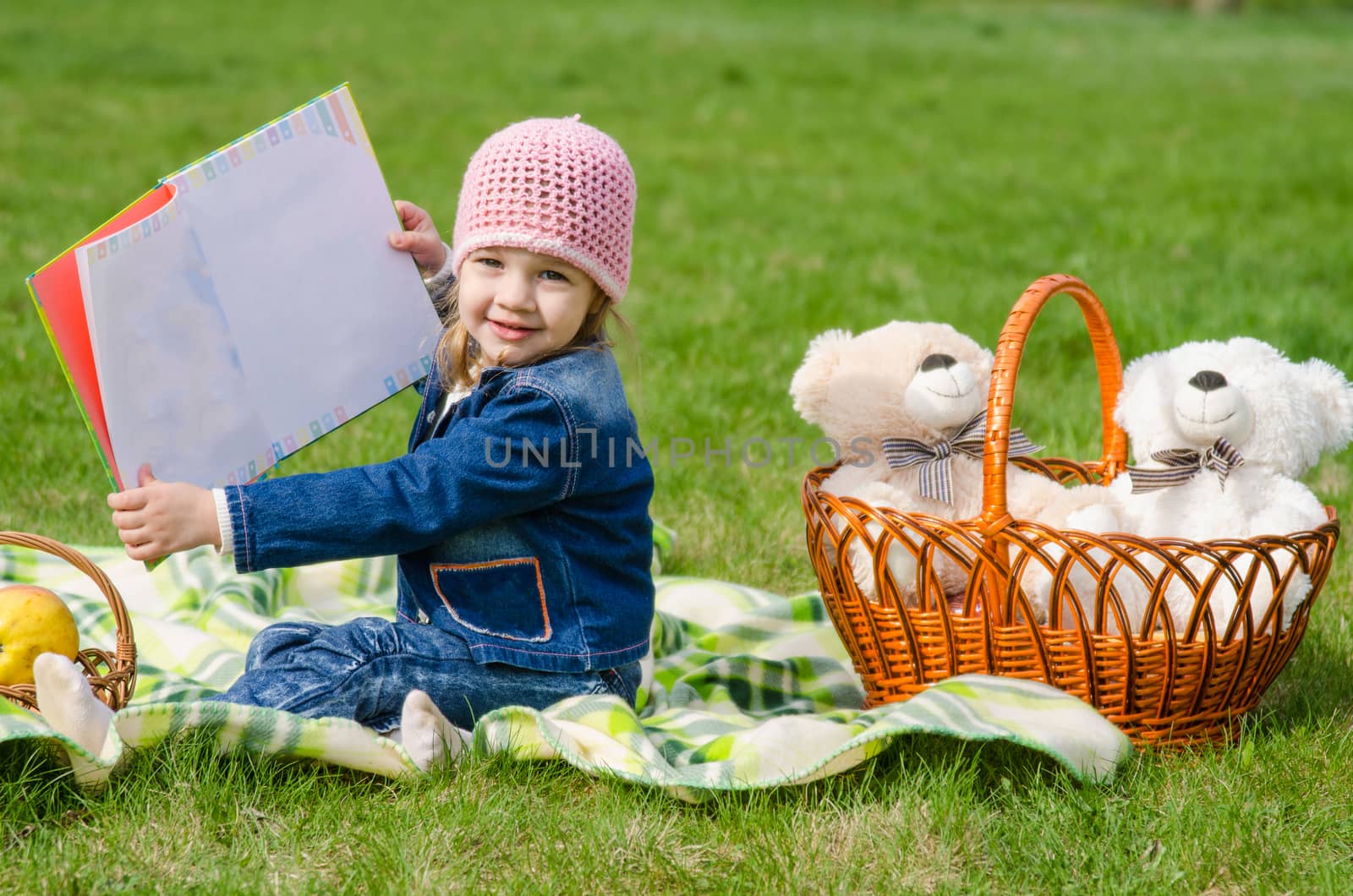 Happy girl showing the book on picnic by Madhourse
