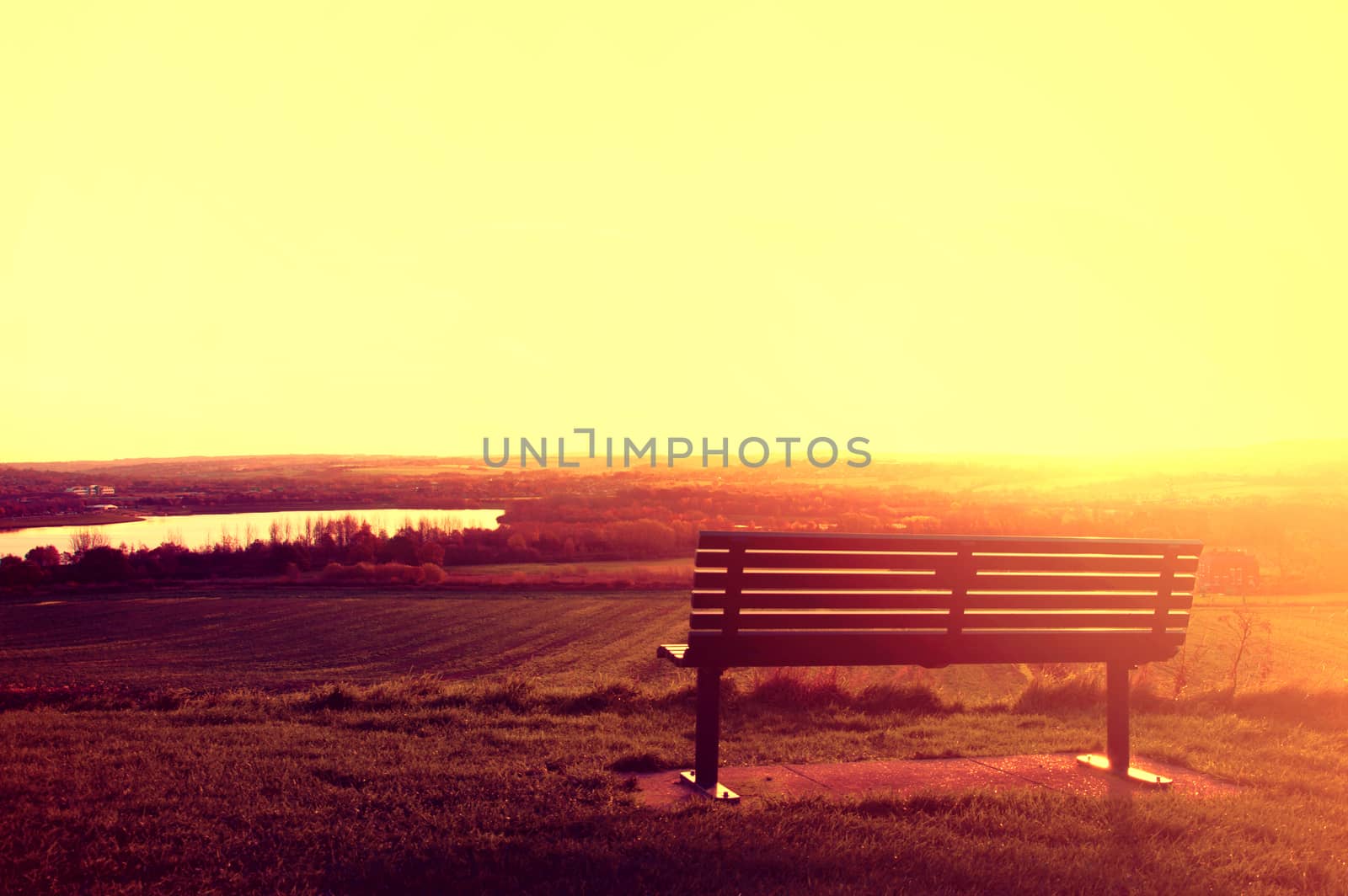 Landscape conceptual image. Alone bench at sunset.
