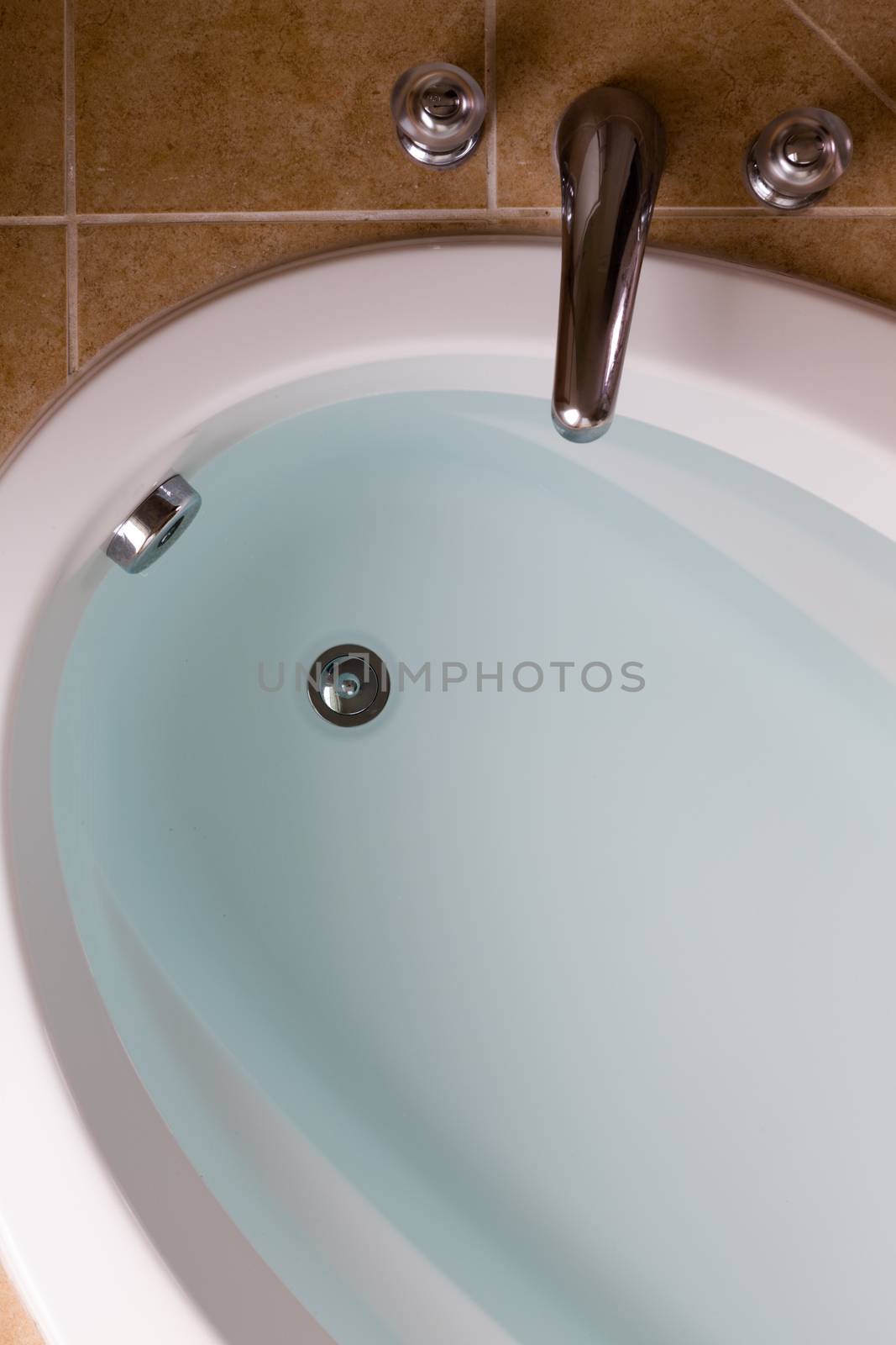 Close up high angle view of a sunken oval bathtub full of clean fresh water ready for a lovely relaxing bath