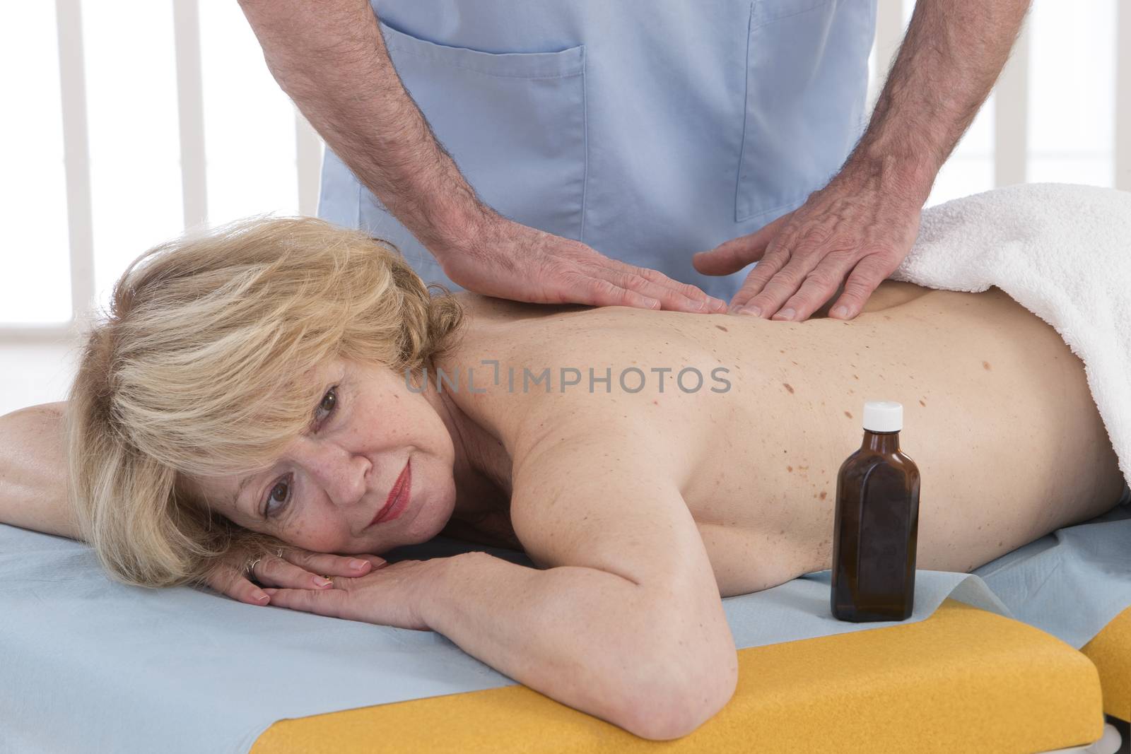 Male physiotherapist massaging woman's back in the medical offic by JPC-PROD