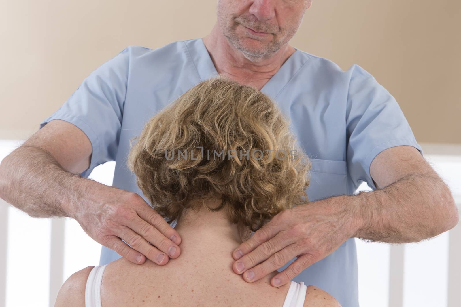 Male physiotherapist massaging a senior woman's shoulders  and neck by JPC-PROD