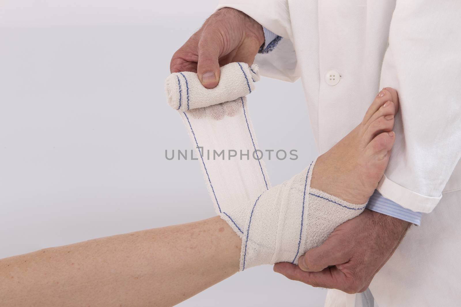 Close-up of male doctor bandaging foot of female patient at doctor's office.