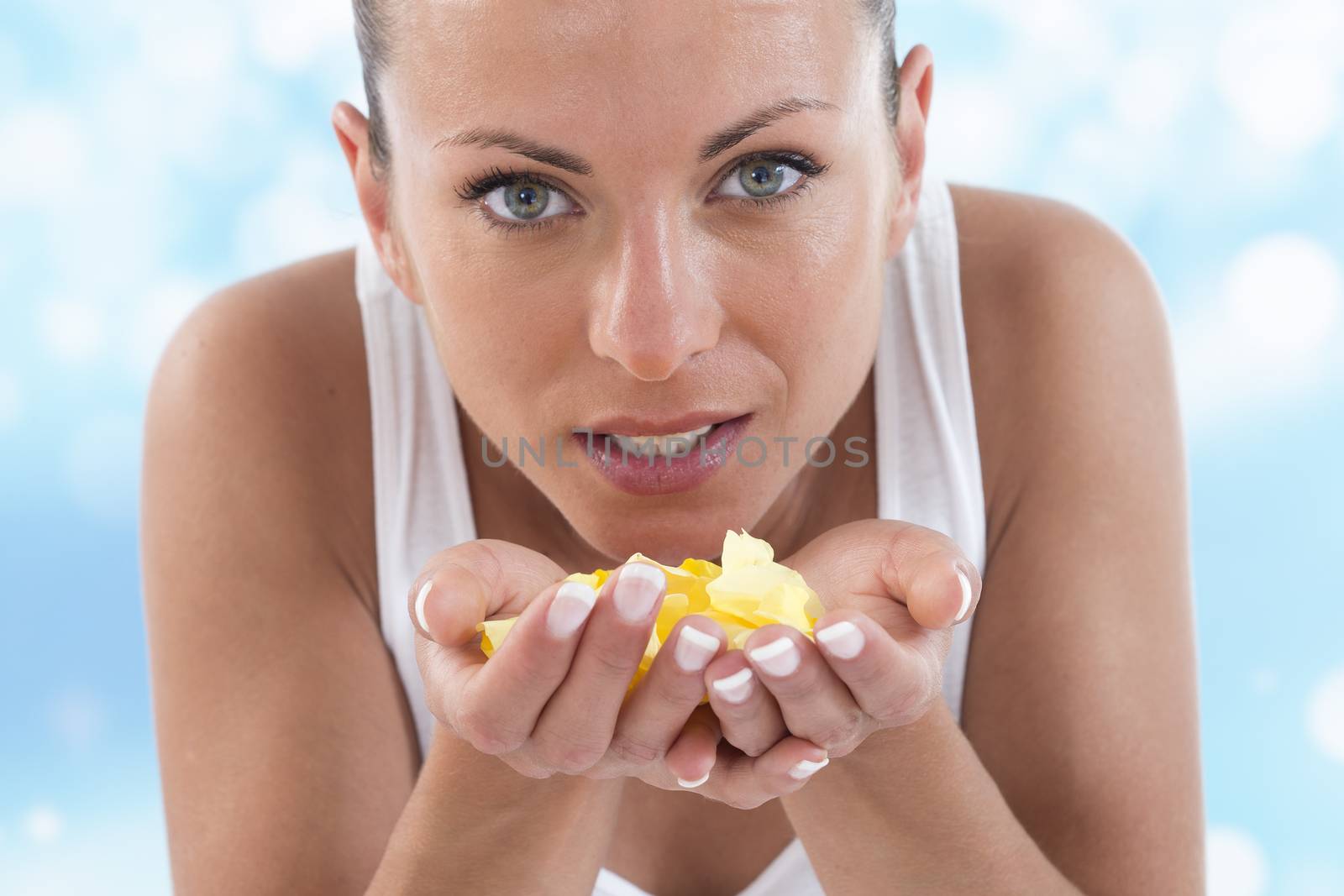 A young girl blowing on rose petals