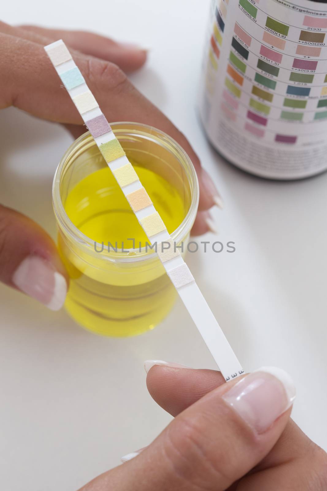 Urine test stripes examined by a young woman at home by JPC-PROD