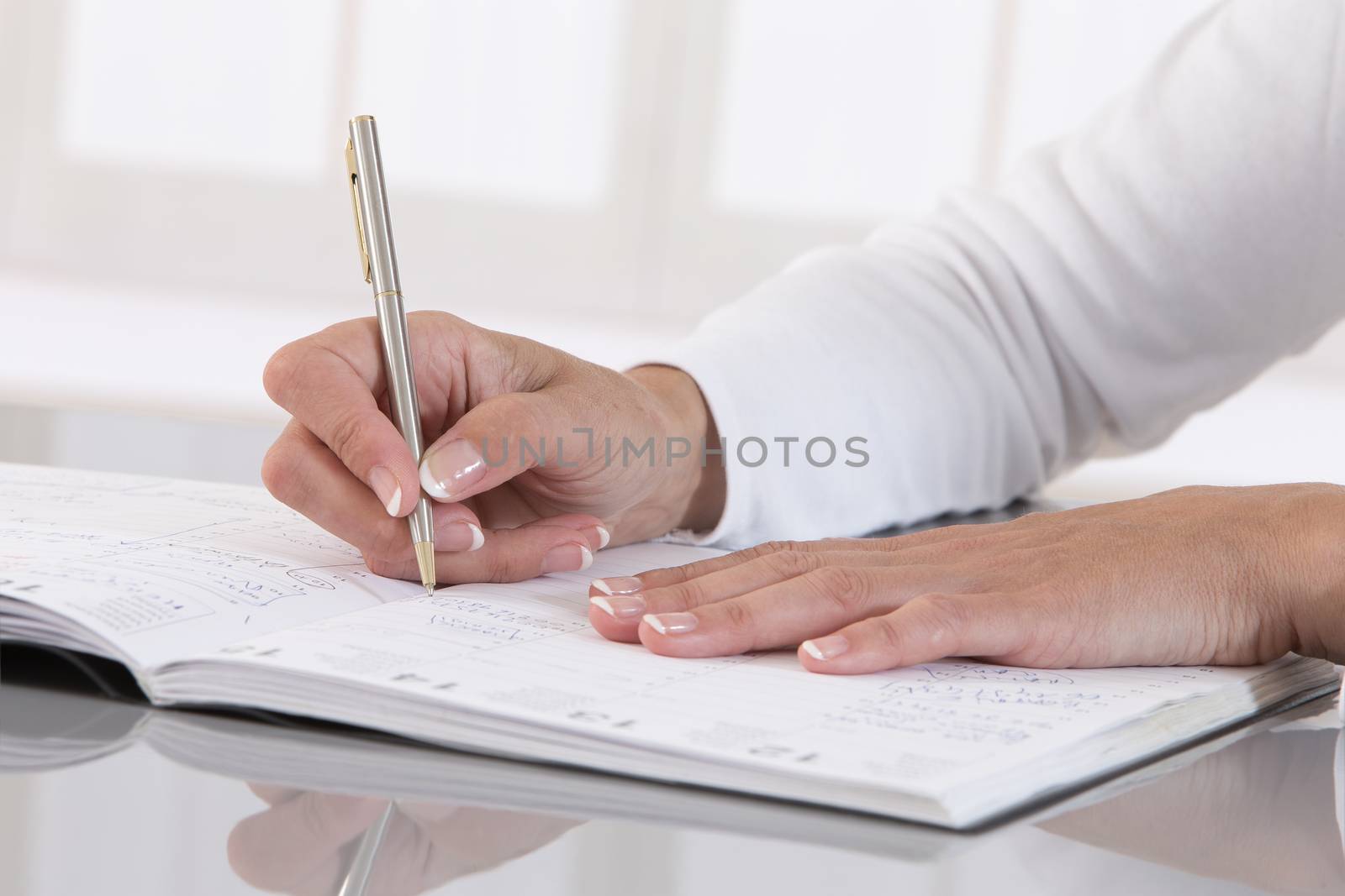 Businesswoman in office noting an appointment in her diary, closeup