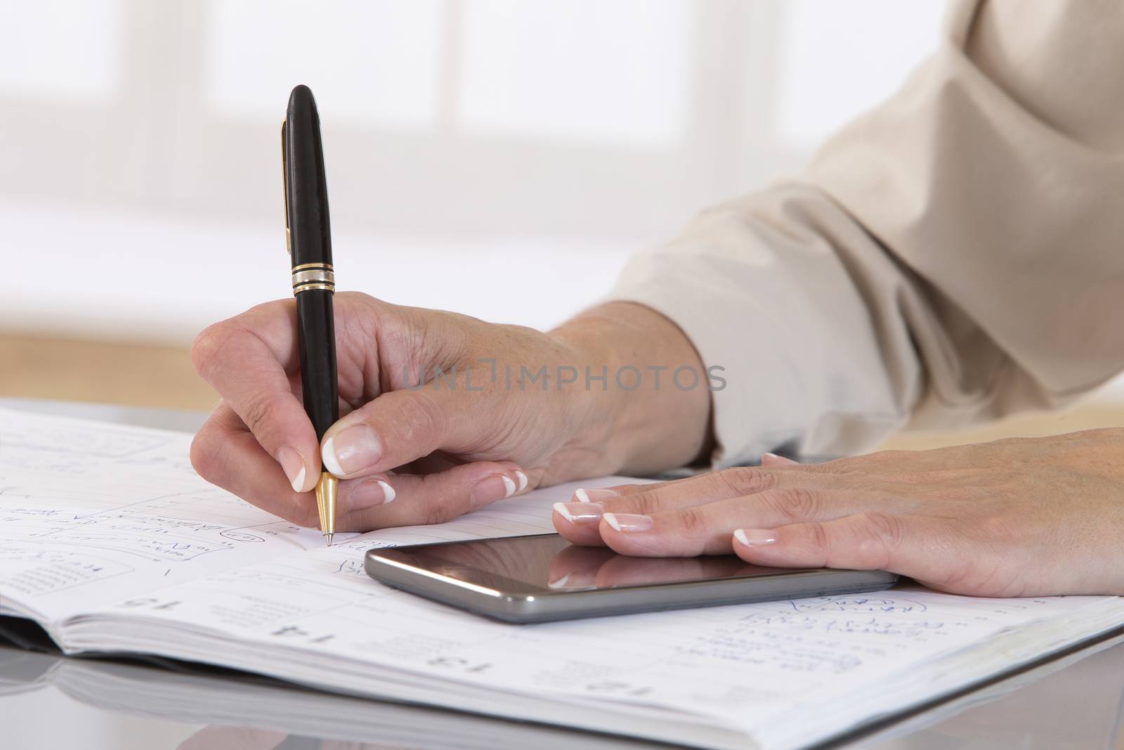 Business woman hand with pen make write notes in notebook and mobile smart phone.