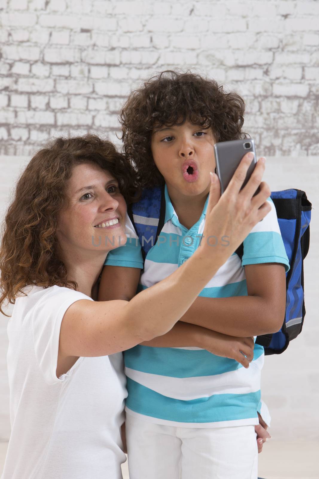 mother and sun are doing selfie by mobile phone before first day of school