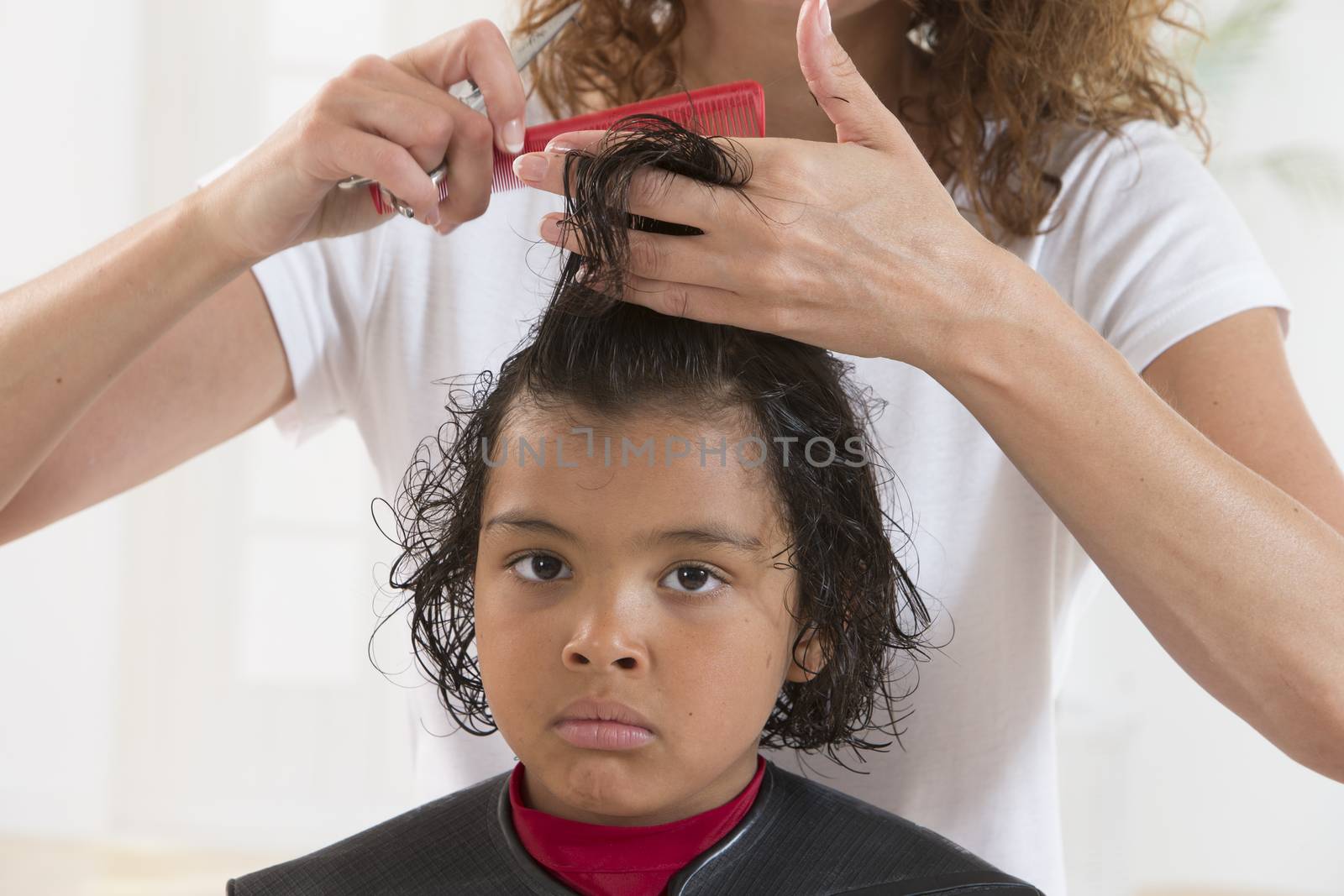 young child with large expressive eyes at the hairdresser having by JPC-PROD