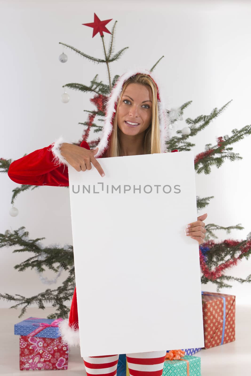 smiling santa woman behind blank board pointing on Christmas bac by JPC-PROD