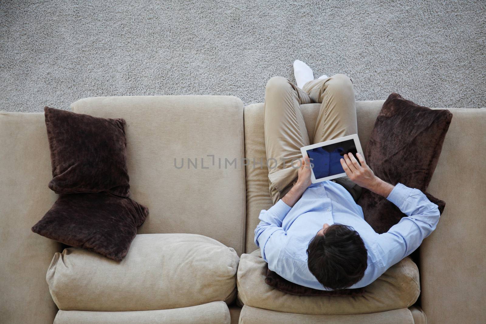 man sitting on couch with tablet by ALotOfPeople