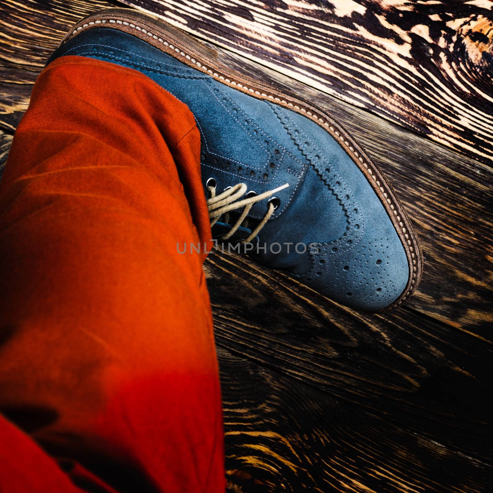 Close up of men's brogues (also known as derbies,gibsons or wingtips) made from blue oiled suede. Orange radiant pants and blue suede shoes