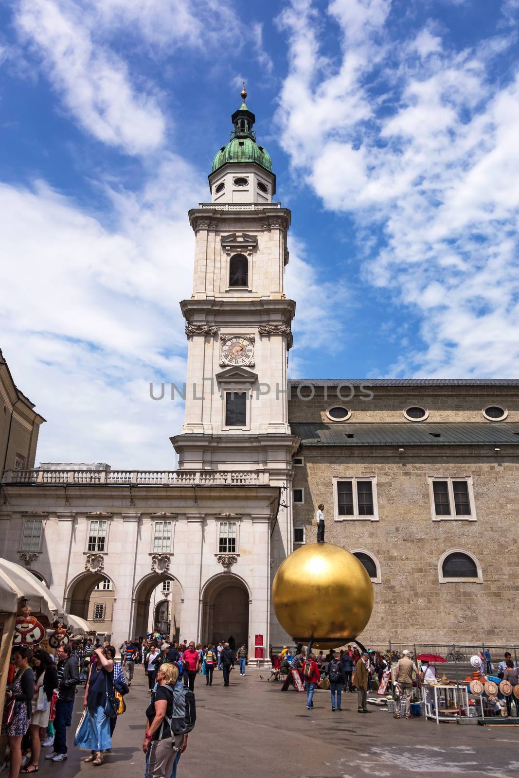 Salzburg, Austria - June 25, 2014: Modern statue at Kapitelplatz. Golden sphere, with a man standing on top, created by sculptor Stephan Balkenhol in 2007