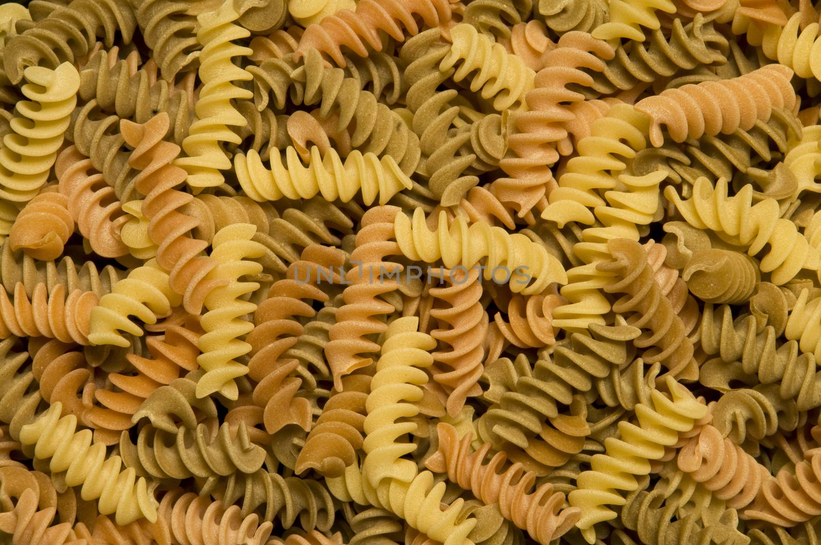 Uncooked multi-colored fusilli, corkscrew-shaped pasta