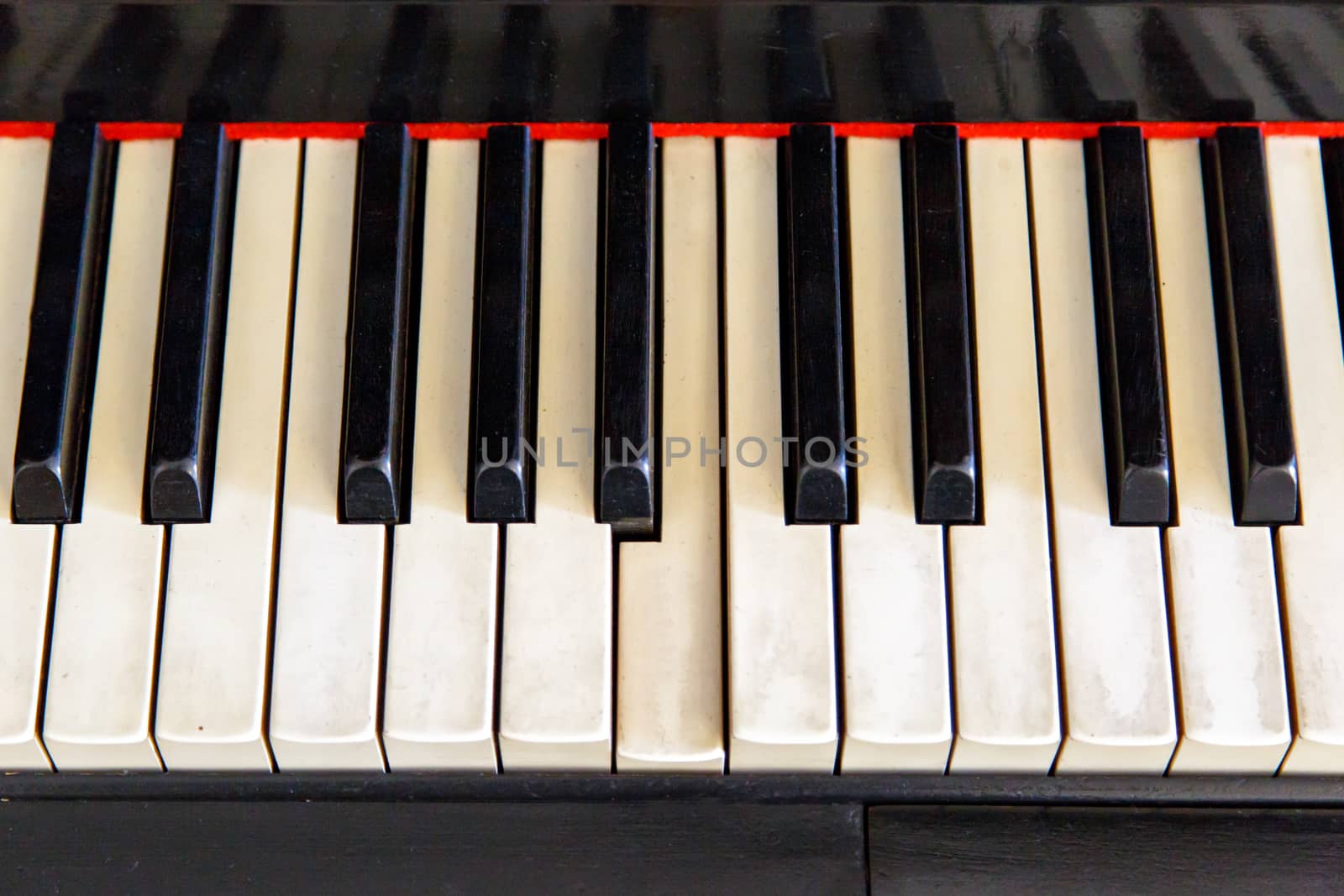 Close up top view of black old piano with white keys on.