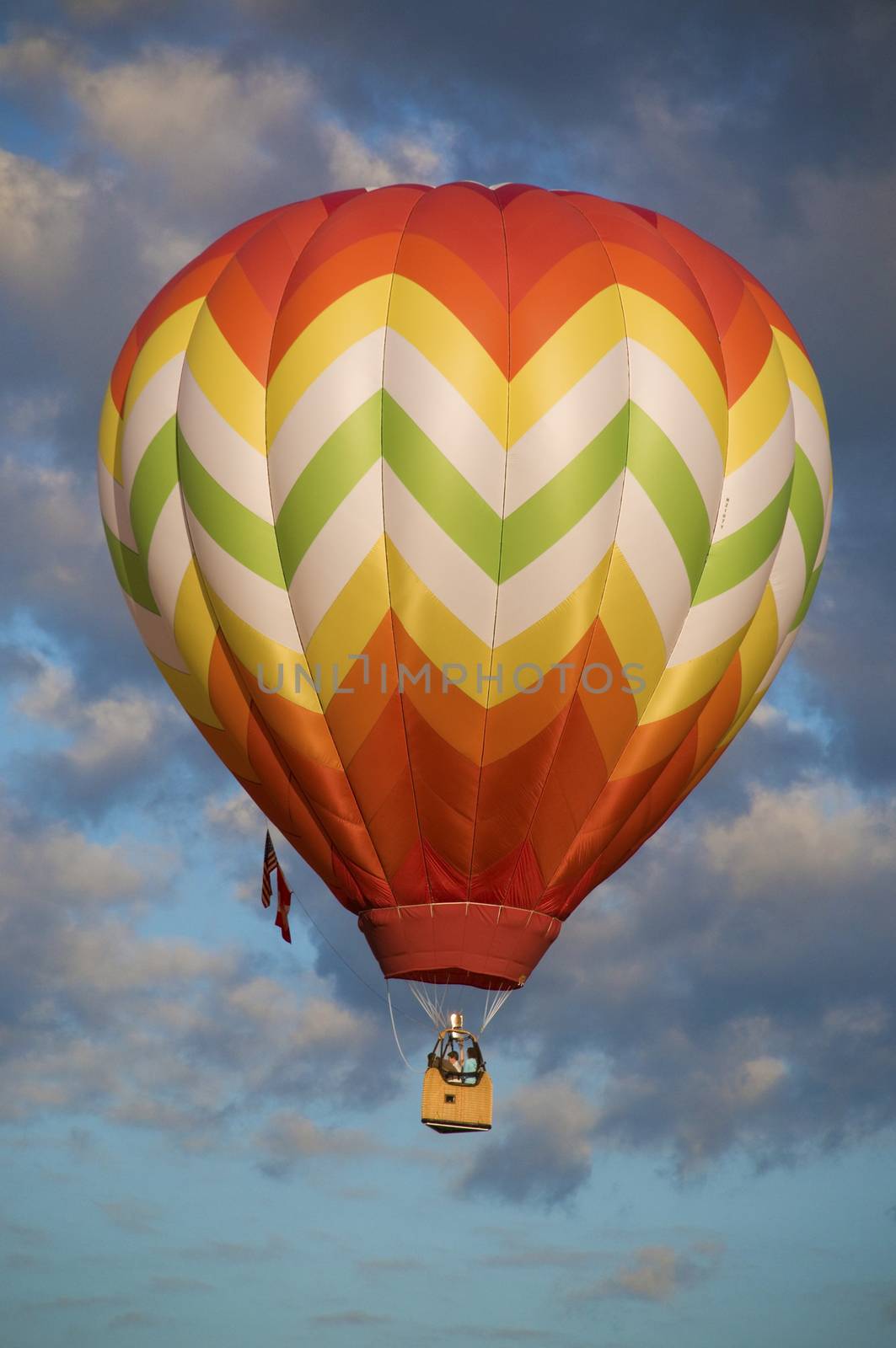 Orange and yellow hot-air balloon floating among clouds