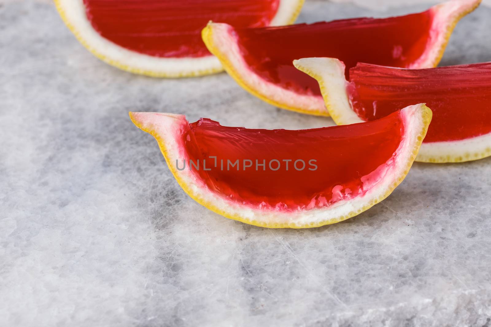 Lemon tequila strawberry jelly (jello) shots on a marble plate. Unusual adult party drinks