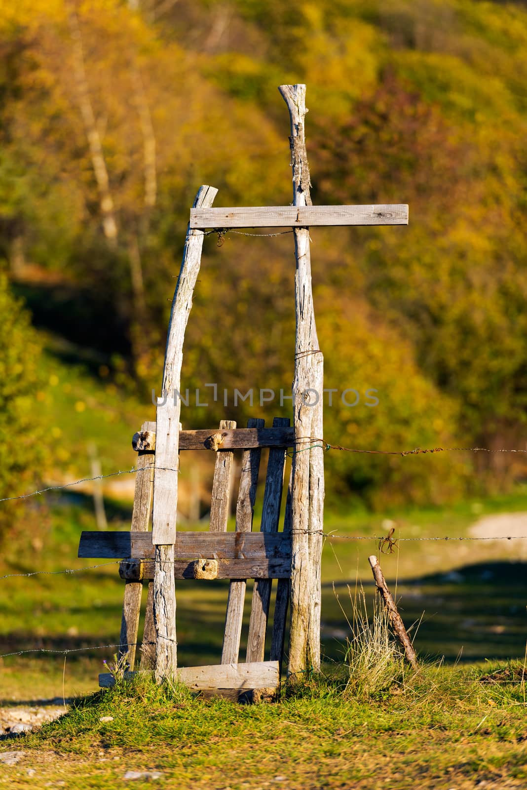 Wooden rustic pedestrian gate and a fence with barbed wire for grazing in mountain. Monte Baldo, Verona, Veneto, Italy