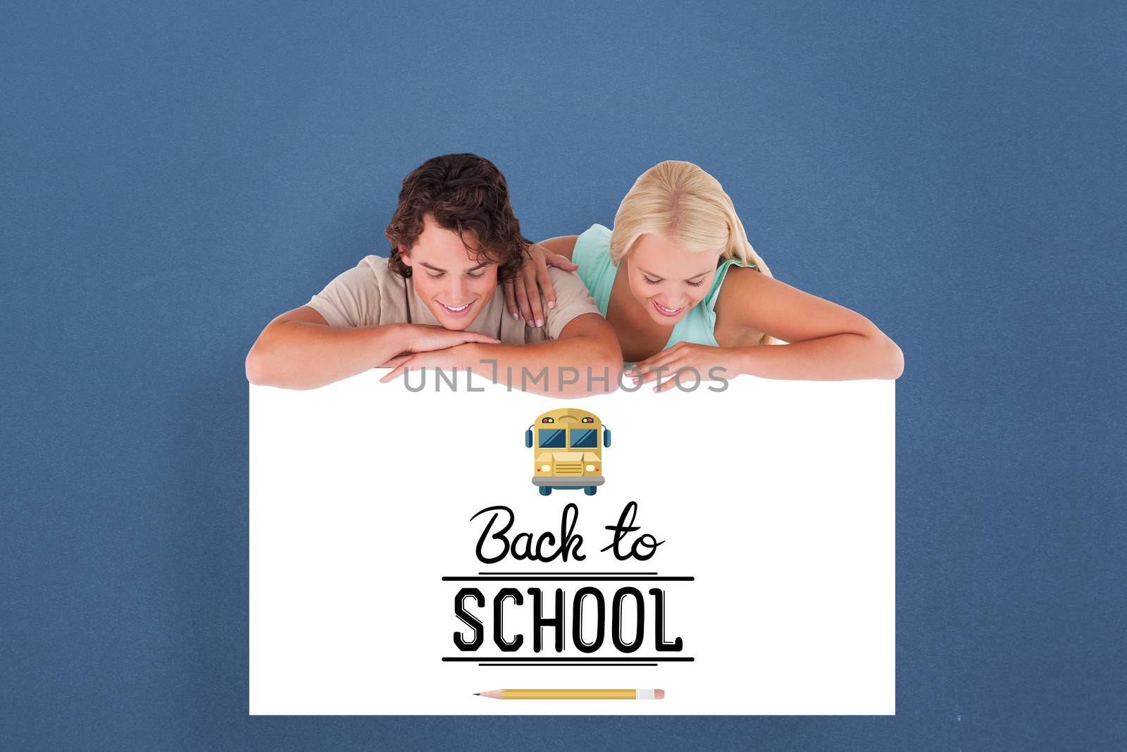 Cute smiling couple leaning on a whiteboard against blue background