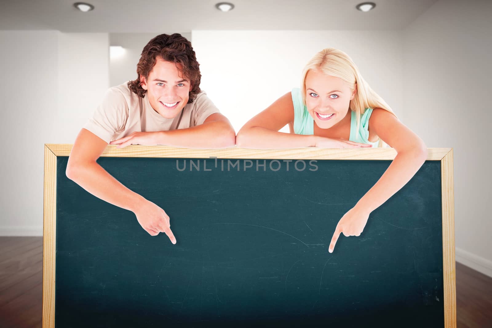 Man and cute woman pointing on a whiteboard against white room with stairs
