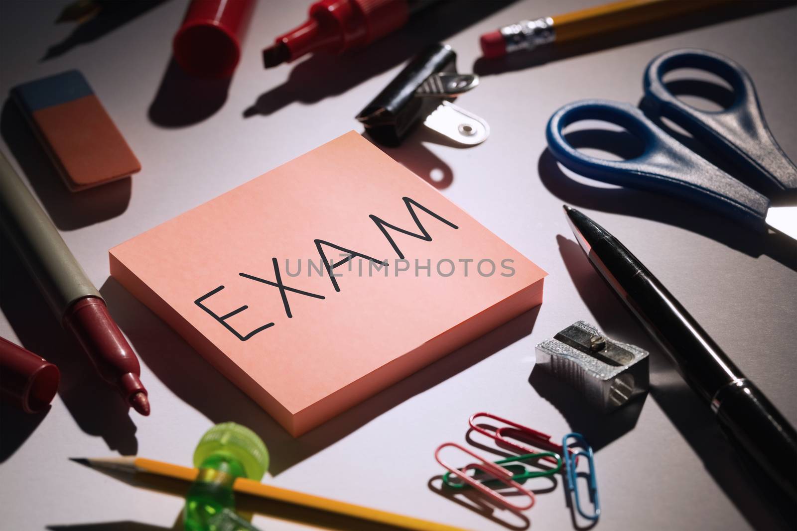 Exam against students table with school supplies by Wavebreakmedia