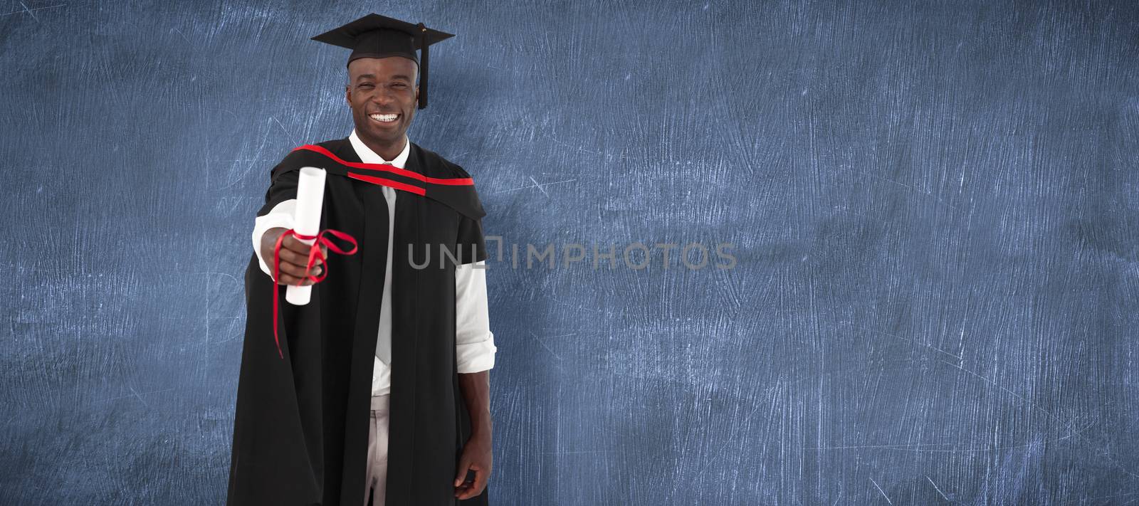 Man smilling at graduation against blue chalkboard