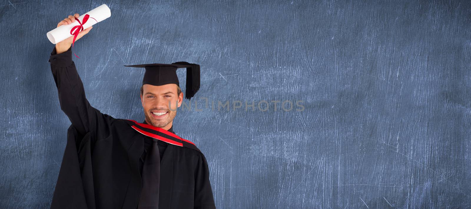 Happy attractive boy after his graduation  against blue chalkboard