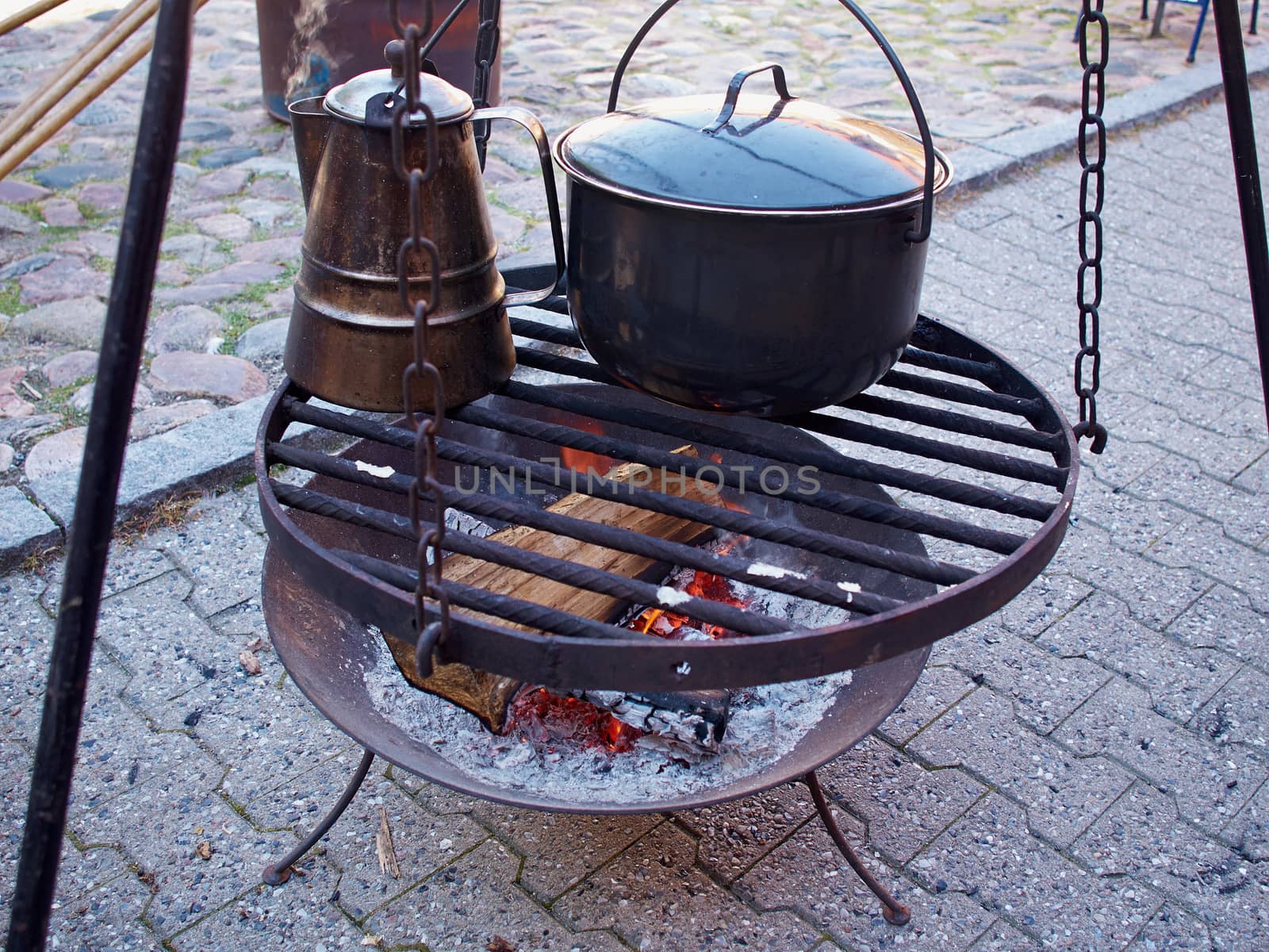 Cooking traditional country soup over burning campfire in cast iron pot            