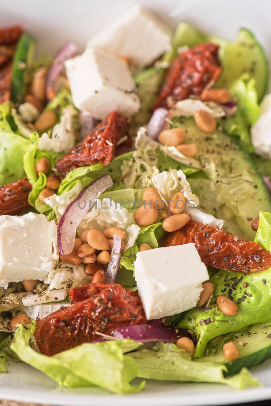 Salad feta cheese lettuce sausage cucumbers and pine nuts