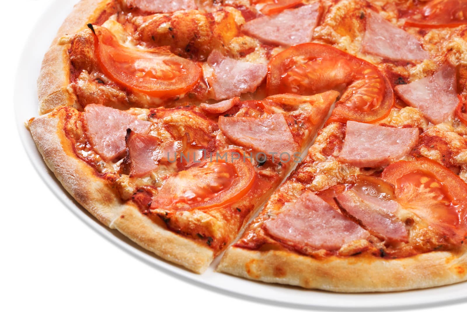 Close up of sliced pizza with tomatoes, meat and ham