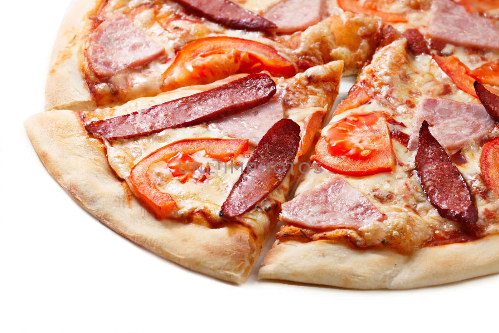 Close up of sliced pizza with tomatoes, meat and sausages