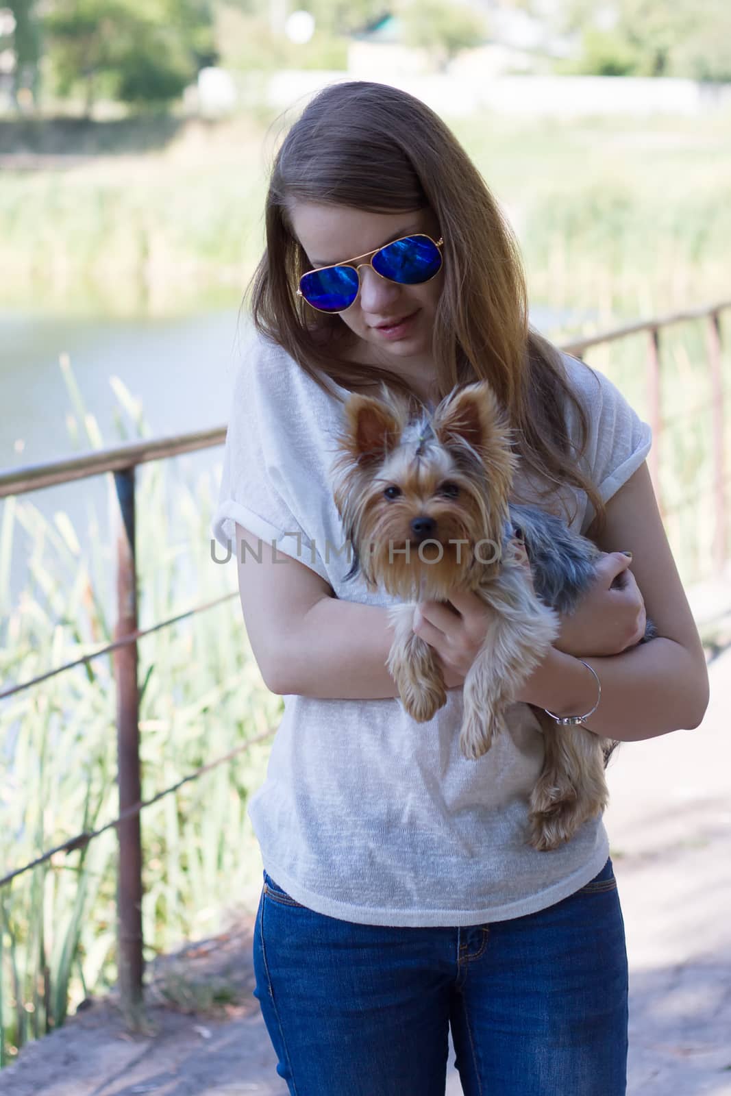 Happy young girl owner with yorkshire terrier dog walking in the park