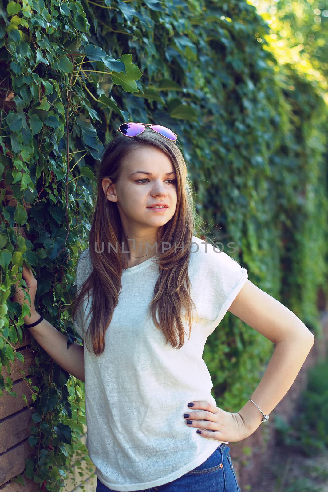 Beautiful smiling girl in white blouse, against green of summer park.