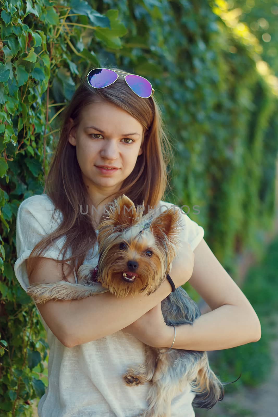 Happy young girl owner with yorkshire terrier dog walking in the park