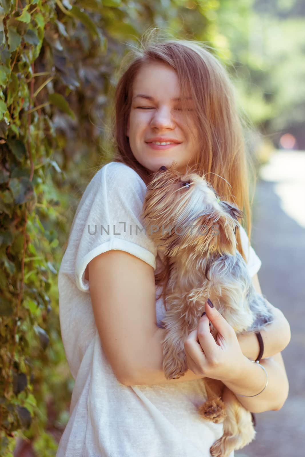 Happy young girl owner with yorkshire terrier dog walking in the park