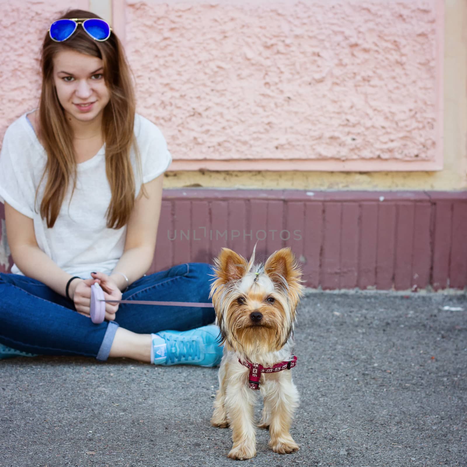 Beautiful sport woman sitting on the floor and holding Yorkshire terrier