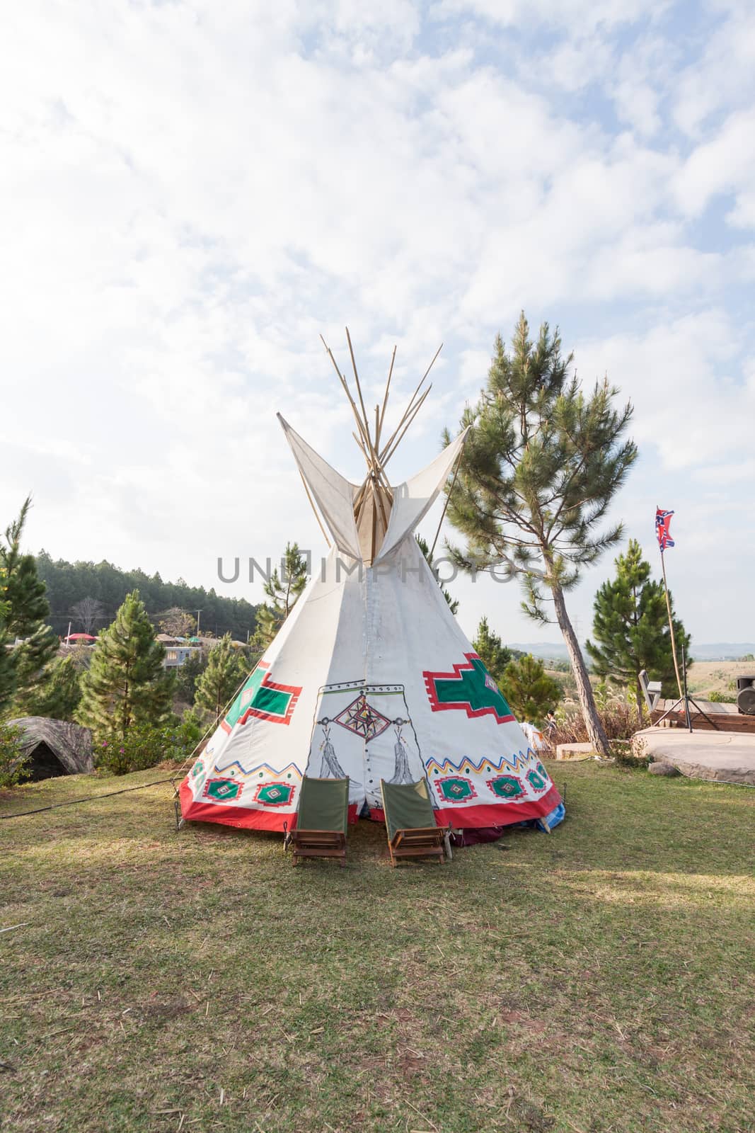 An indian teepee set up in a meadow among pine wood by kritsada1992